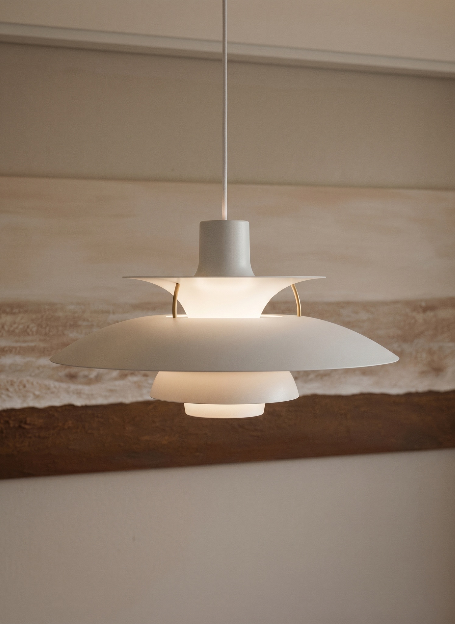 A white layered pendant lamp glowing above an abstract landscape painting