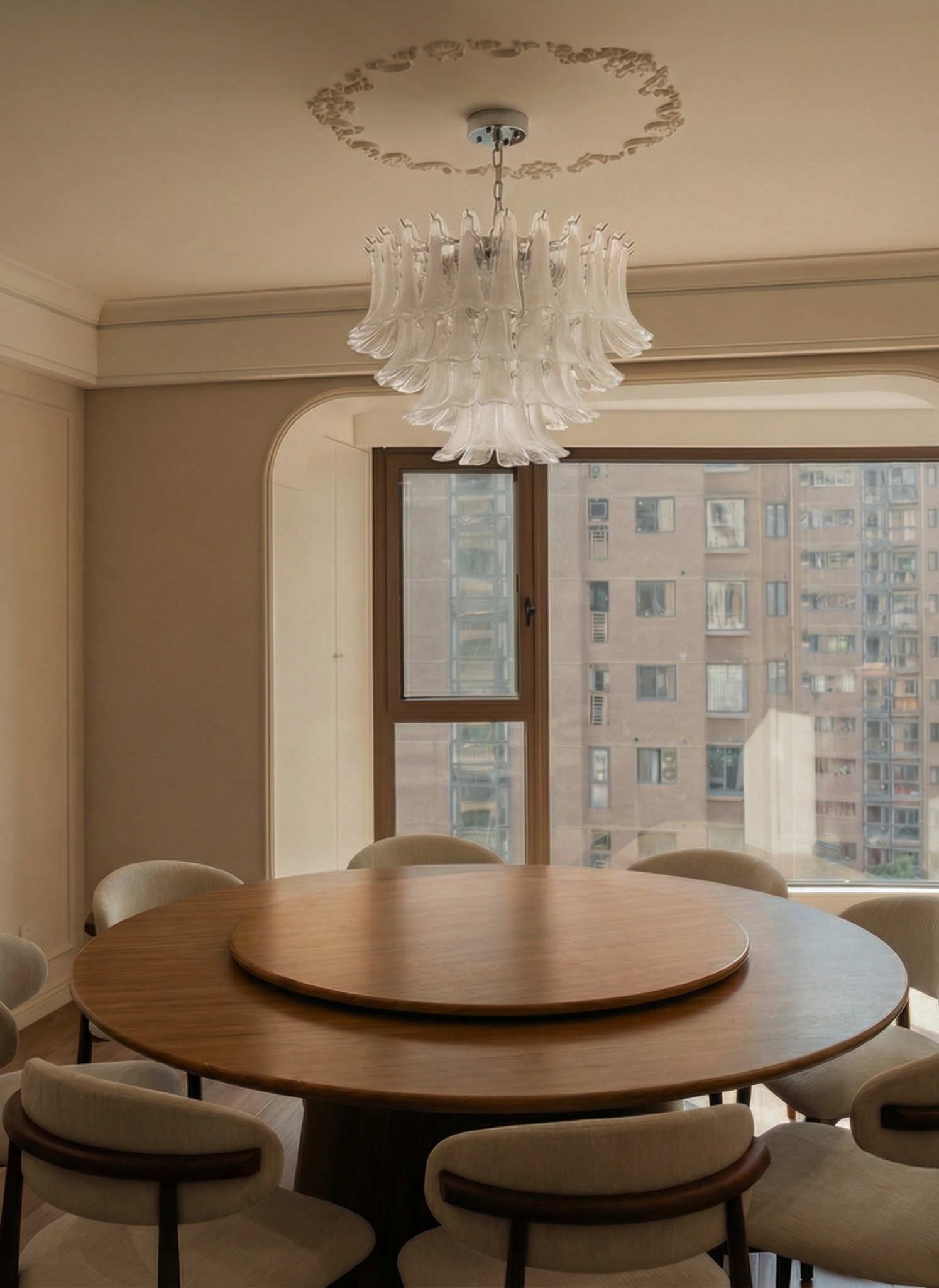 Round oak dining table with eight chairs, a white glass chandelier and a window onto the city