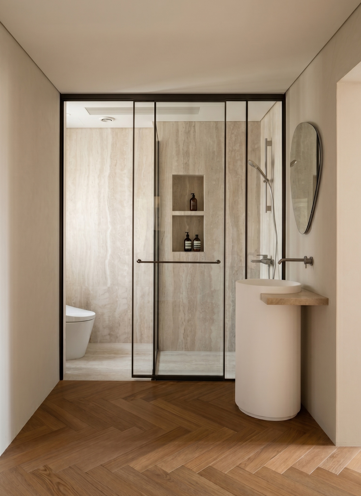Guest ensuite with a pedestal sink, black-framed glass partition and herringbone wood floor